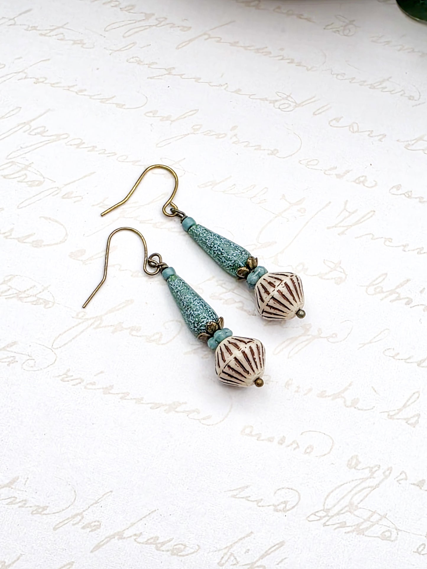 Pair of earrings with turquoise and bronze beads on a white background