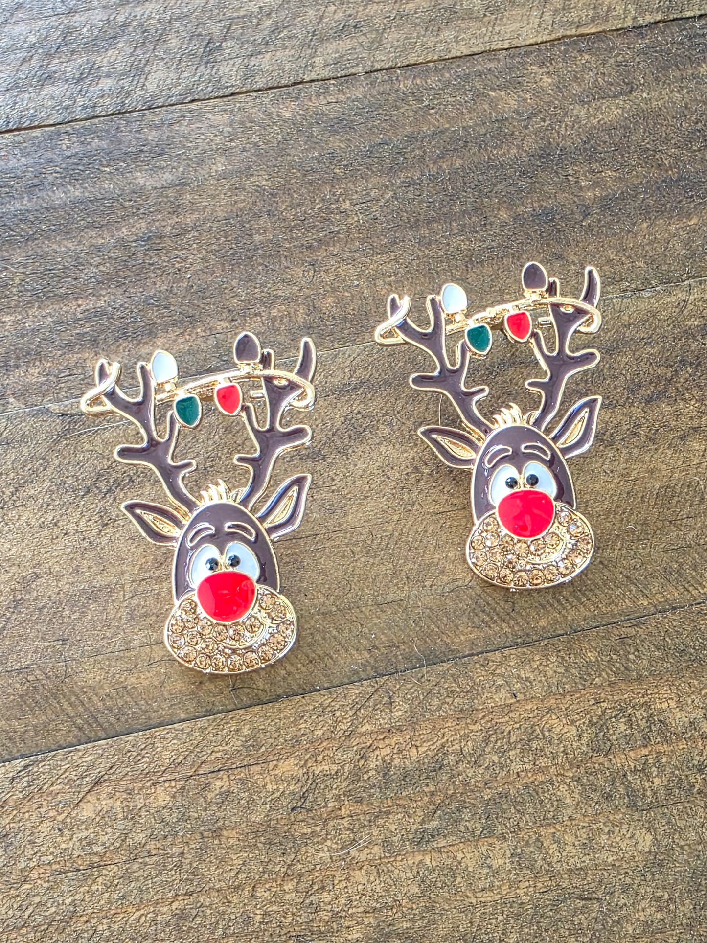 Two reindeer-shaped earrings on a wooden surface