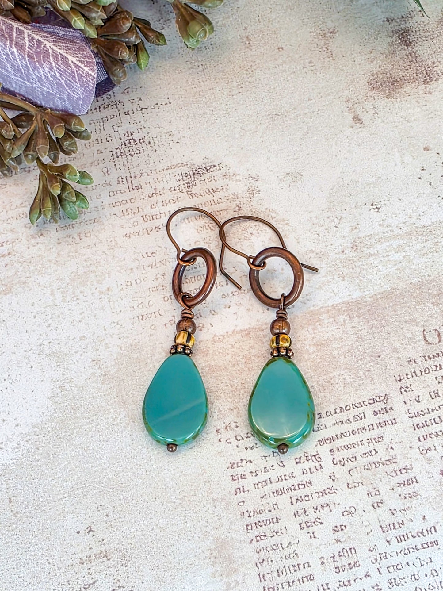 Handcrafted aqua Czech glass teardrop earrings with antiqued copper circles and brass accents.