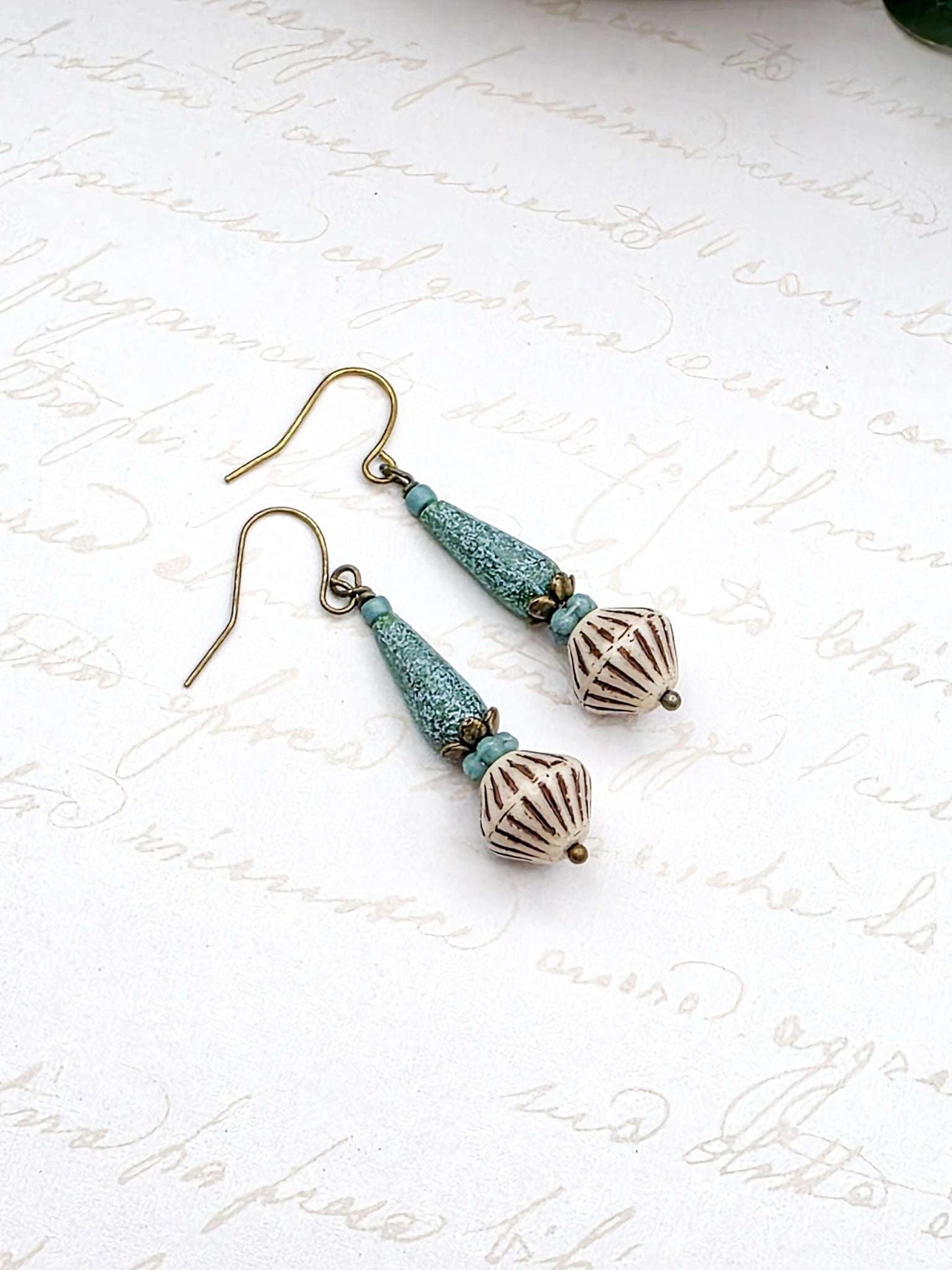 Pair of earrings with turquoise and bronze beads on a white background