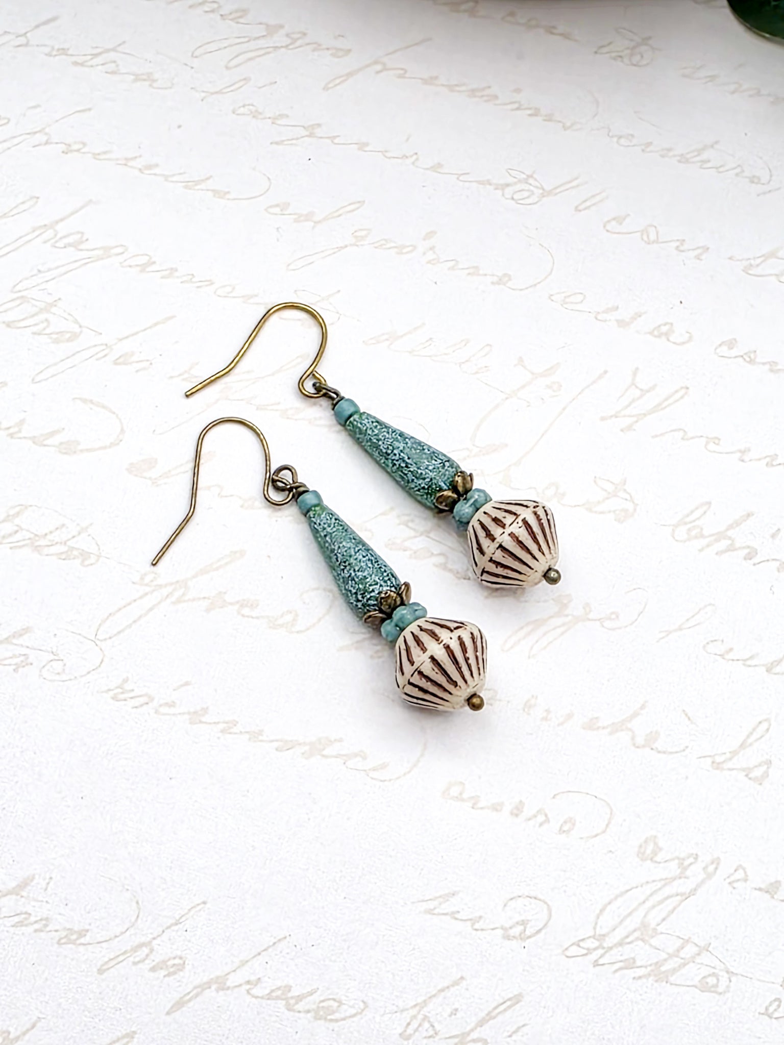 Pair of earrings with turquoise and bronze beads on a white background