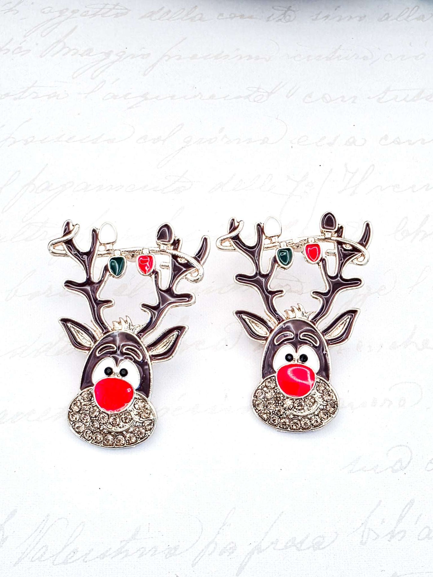 Pair of reindeer-shaped earrings with red noses on a white background