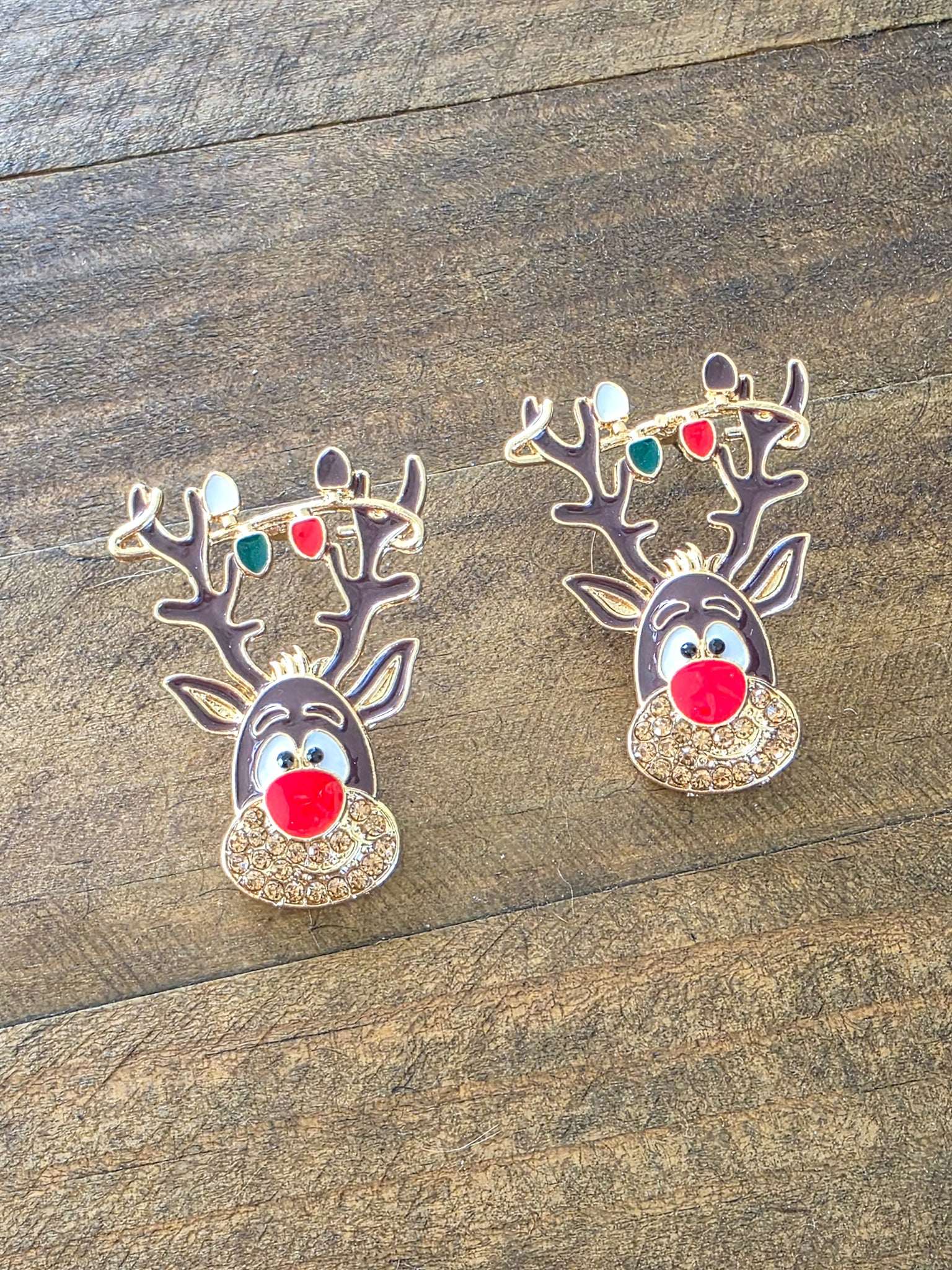 Two reindeer-shaped earrings on a wooden surface