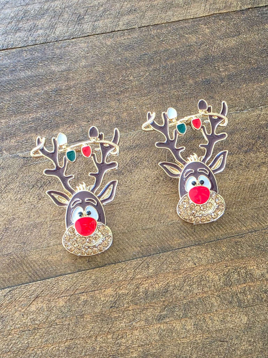 Two reindeer-shaped earrings on a wooden surface