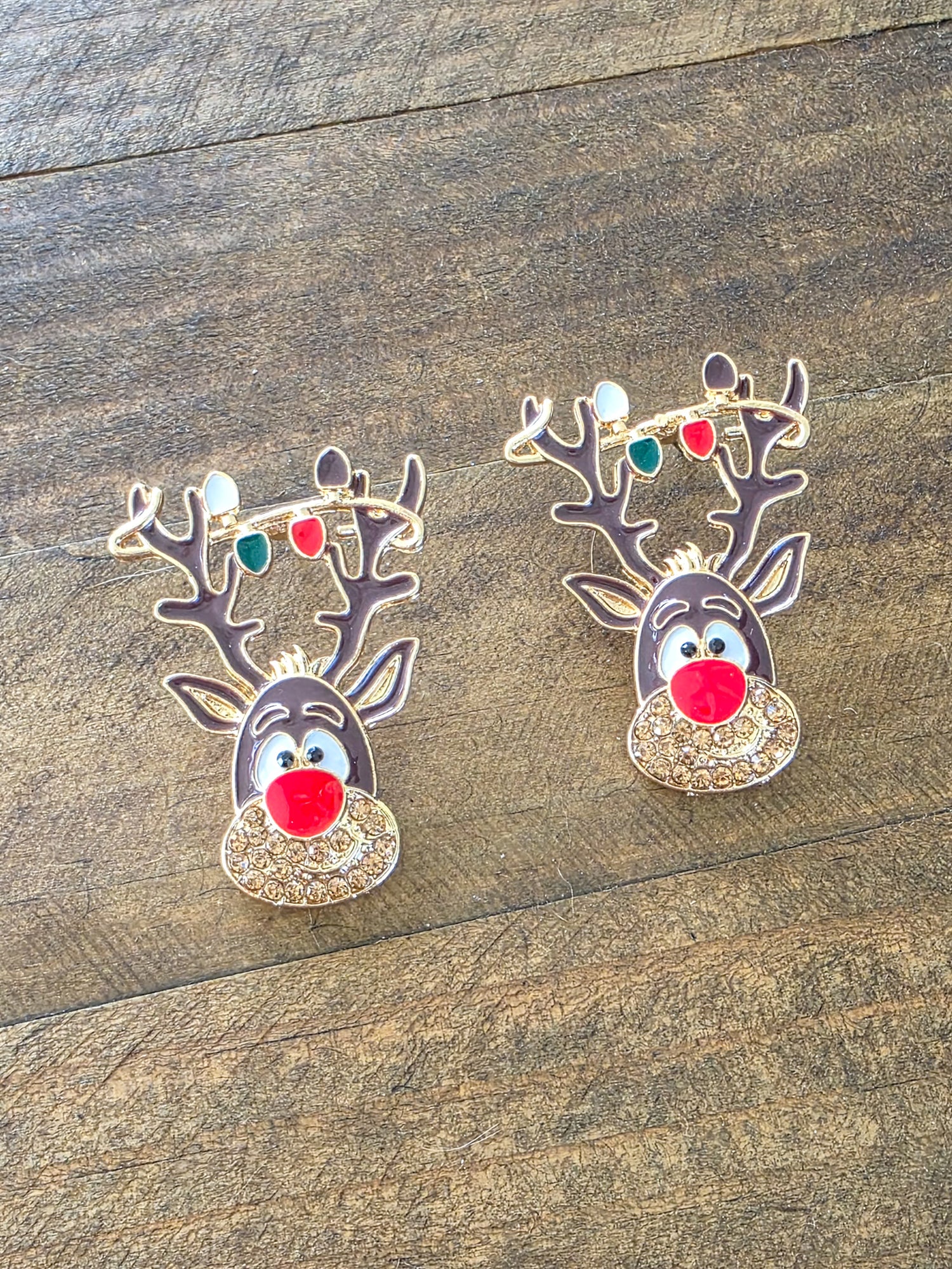 Two reindeer-shaped earrings on a wooden surface