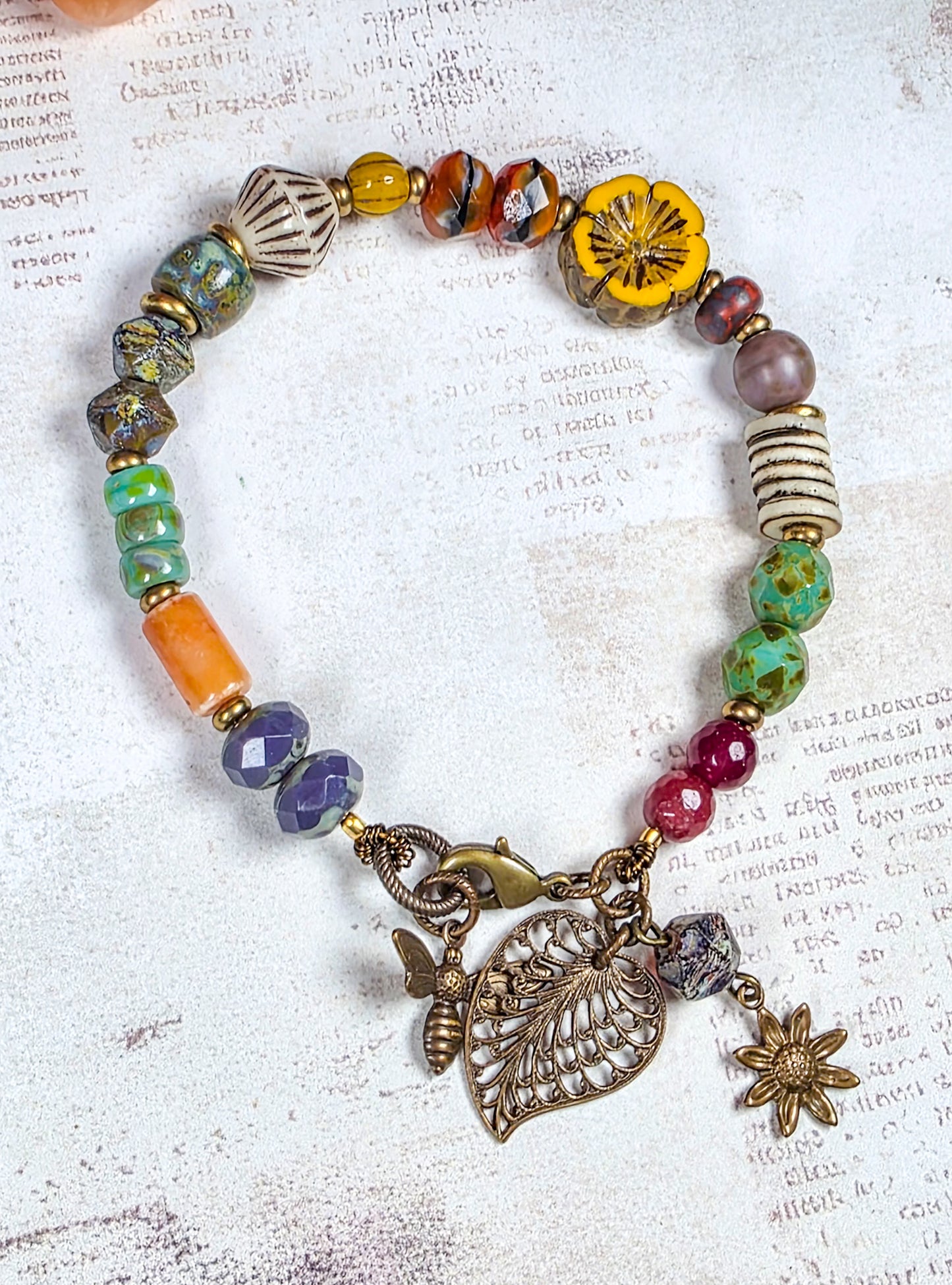 Colorful Czech glass bracelet with antiqued brass leaf flower and bee charms