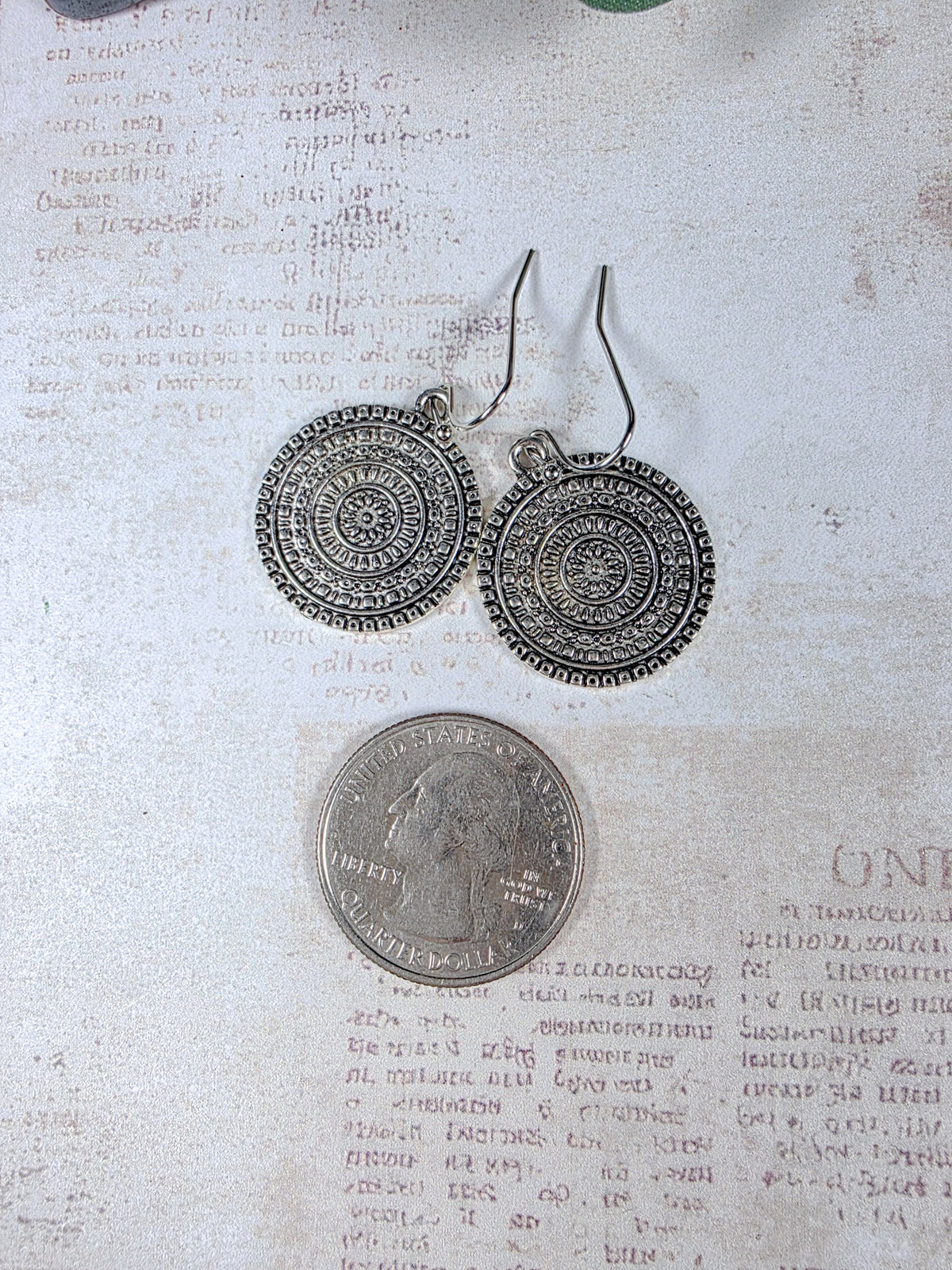 Antiqued silver medallion earrings shown beside a quarter for size